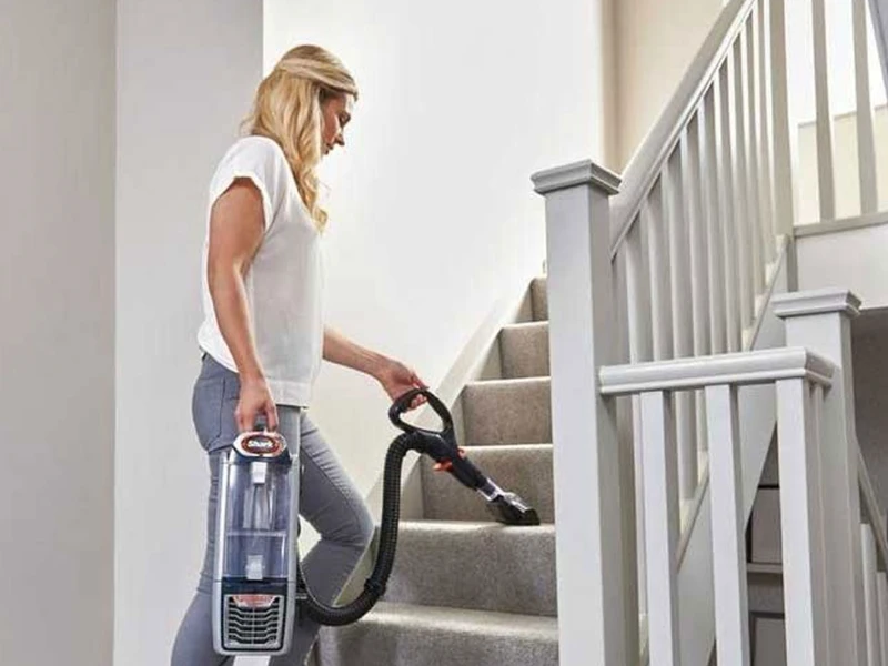 Lady easily holding up the Shark NV352 vacuum and cleaning stairs