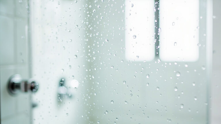 Clean glass shower door with chrome hardware showing water beading effect after proper cleaning