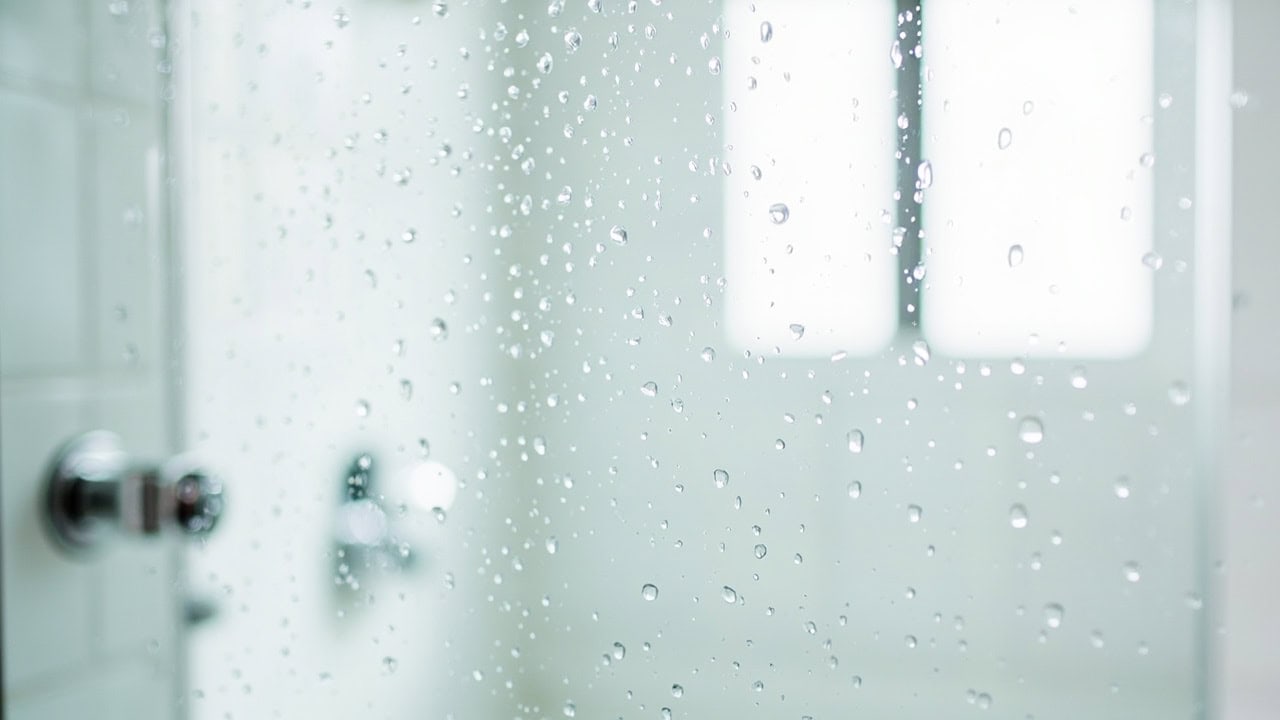 Clean glass shower door with chrome hardware showing water beading effect after proper cleaning