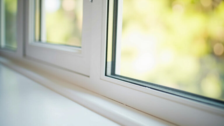 Clean white vinyl window track channel with morning light reflecting off nearby glass surface
