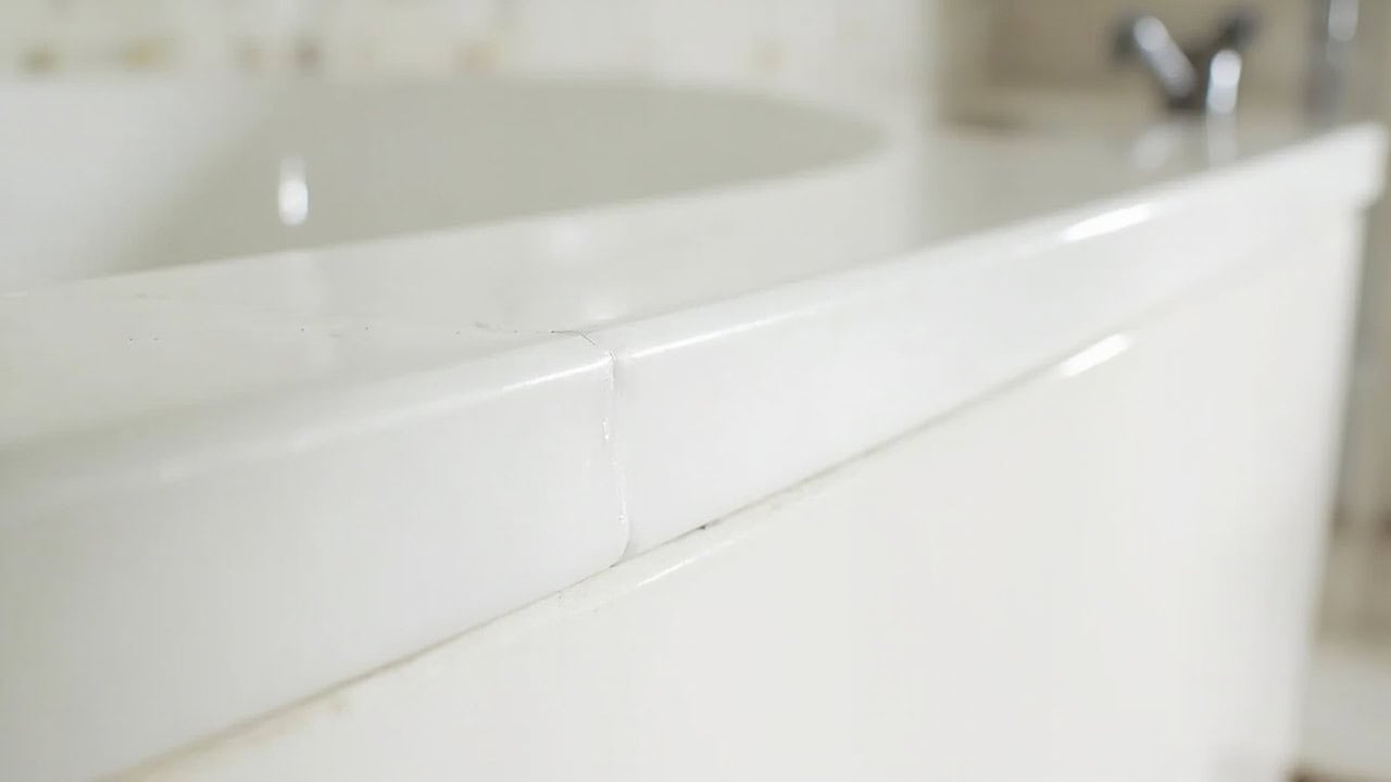 "Fresh silicone caulk seal along bathtub edge with tiled wall background"