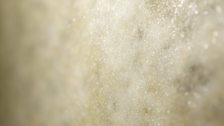 "Close-up of soap scum buildup showing cloudy white mineral deposits and water spots on a glass shower door surface"