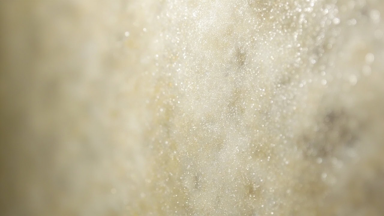 "Close-up of soap scum buildup showing cloudy white mineral deposits and water spots on a glass shower door surface"