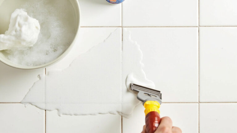 "Wax buildup on ceramic tile floor with plastic scraper, hot soapy water, and mineral spirits ready for removal"