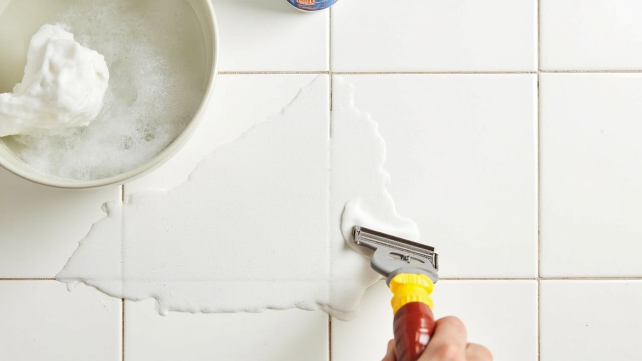 "Wax buildup on ceramic tile floor with plastic scraper, hot soapy water, and mineral spirits ready for removal"