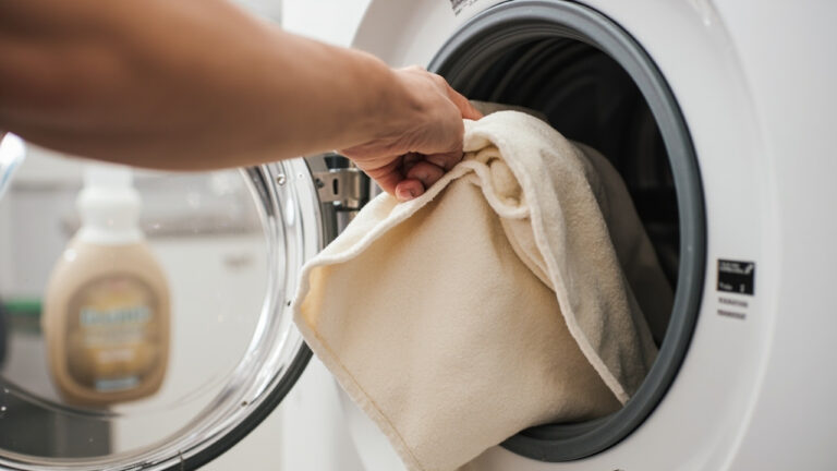 Microfiber couch cover loaded into washing machine on gentle cycle with cold water settings
