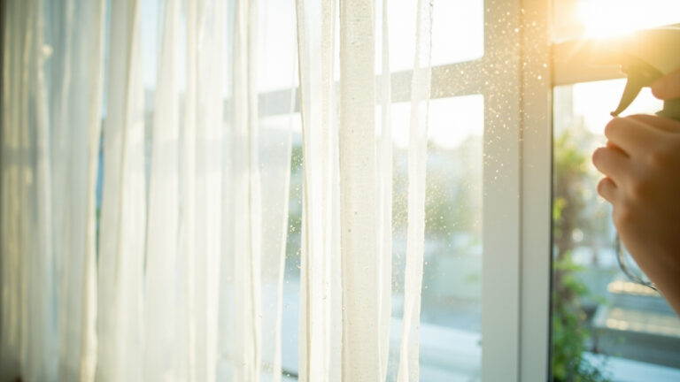 "Delicate white sheer curtains being gently hand-washed in a sink with clean water"