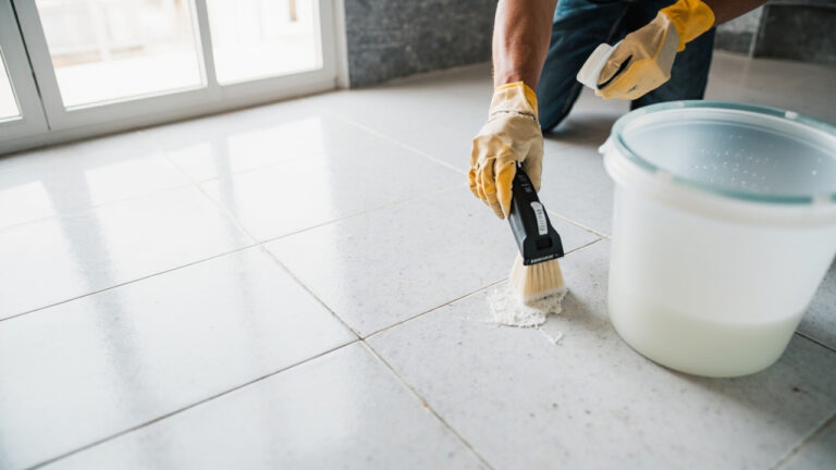 Tile grout cleaning professional scrubbing grout lines between porcelain tiles with stiff-bristled brush