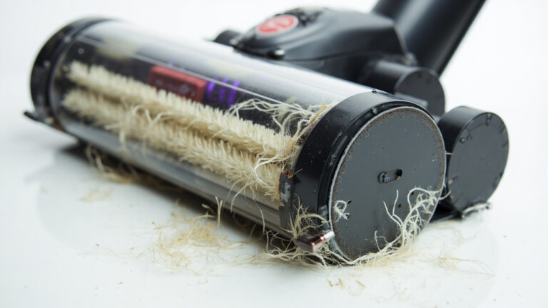 "Vacuum brush roll with tangled debris and worn bristles causing poor dirt pickup"